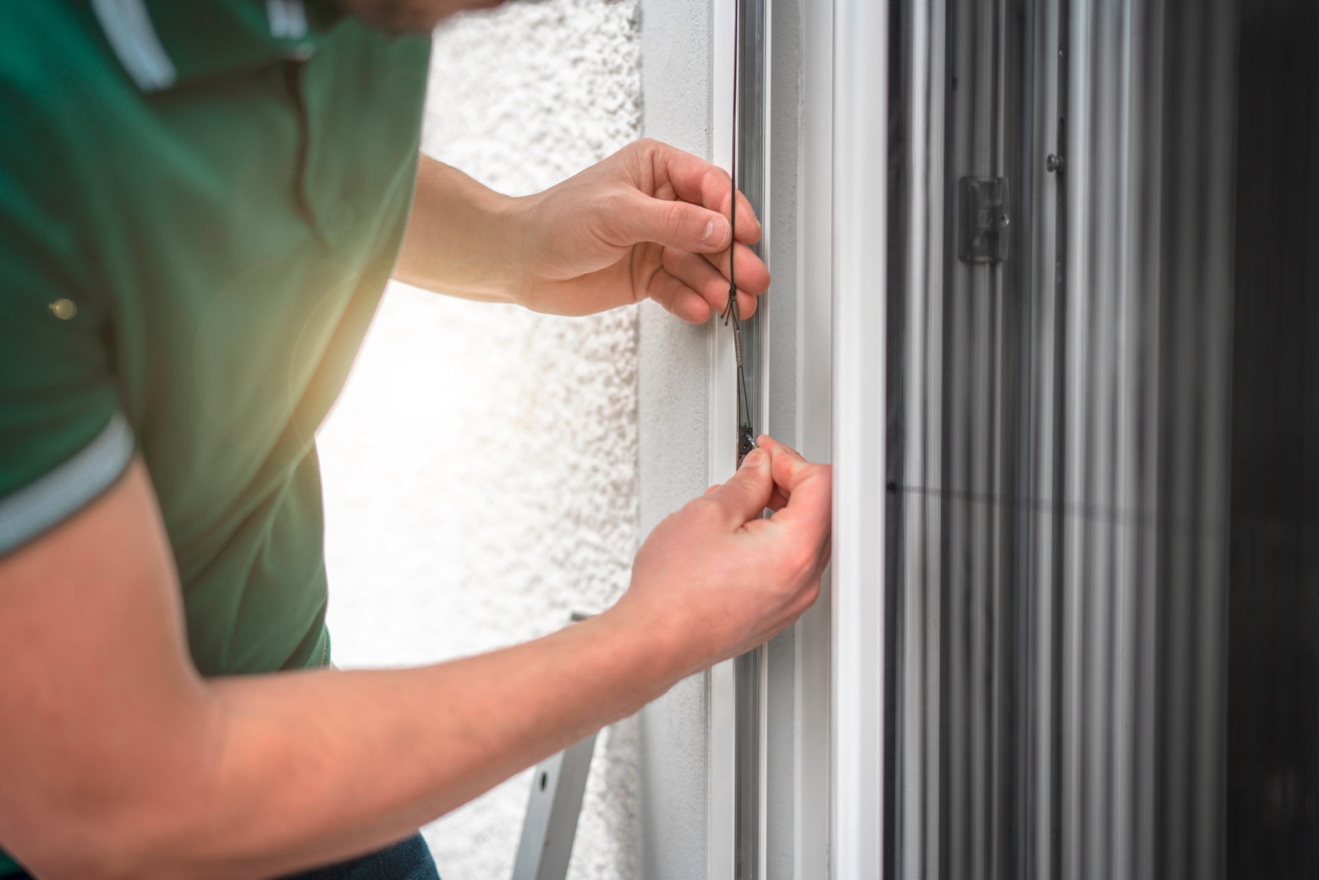 freundlicher Handwerker montiert Insektenschutzgitter bei einem Kunden zu Hause, freundlicher Handwerker montiert Insektenschutzgitter bei einem 